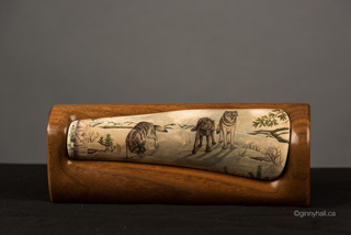 A scrimshaw peice by Ginny Hall 						 		depicting three wolves in a snowy forest.